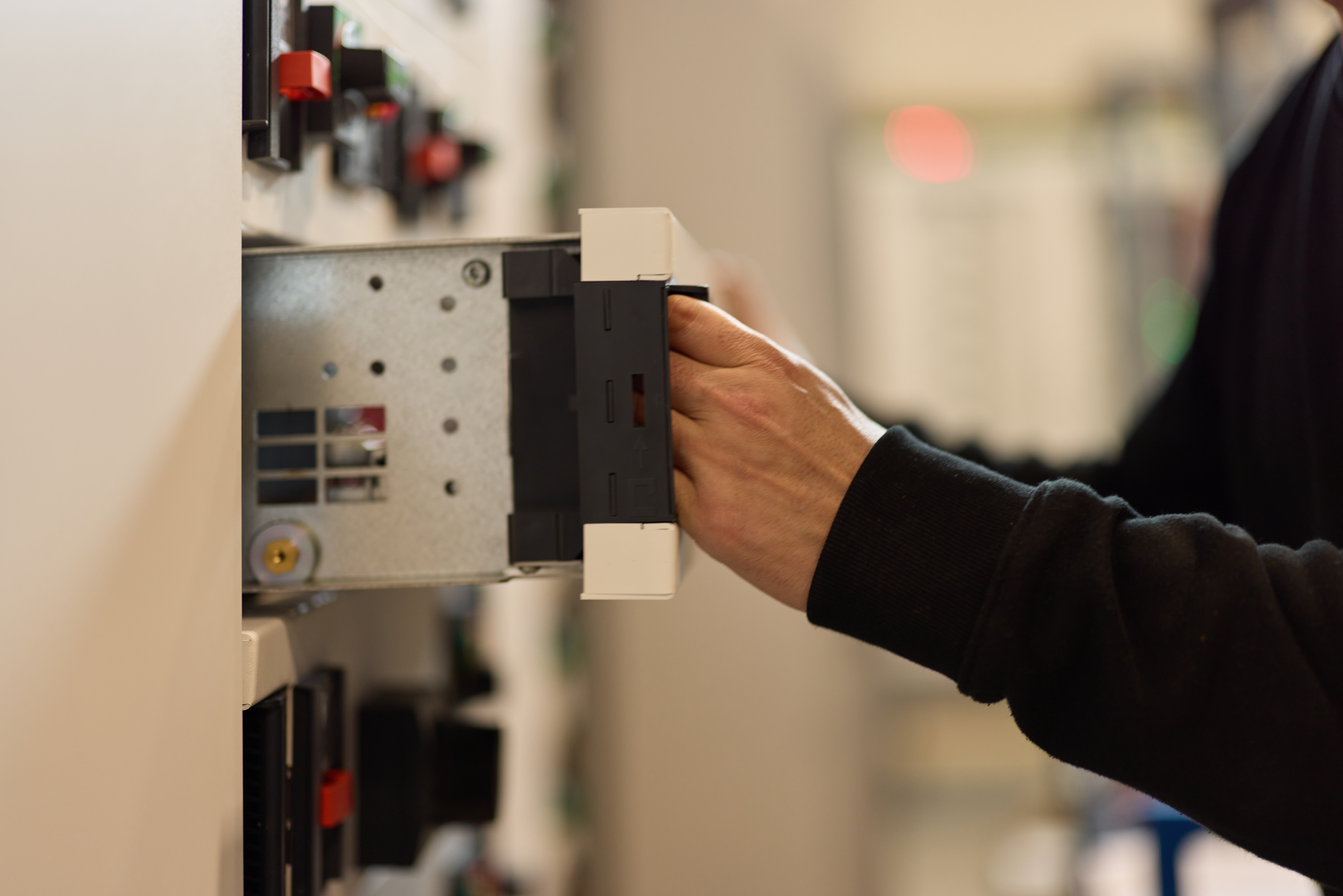 A technician adjusting a circuit breaker in an electrical panel.